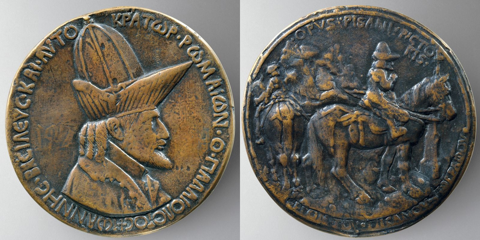 Le due facce di una medaglia in bronzo: a sinistra, un uomo barbuto di profilo sotto un alto cappello a becco; a destra, due cavalieri davanti a una croce.
